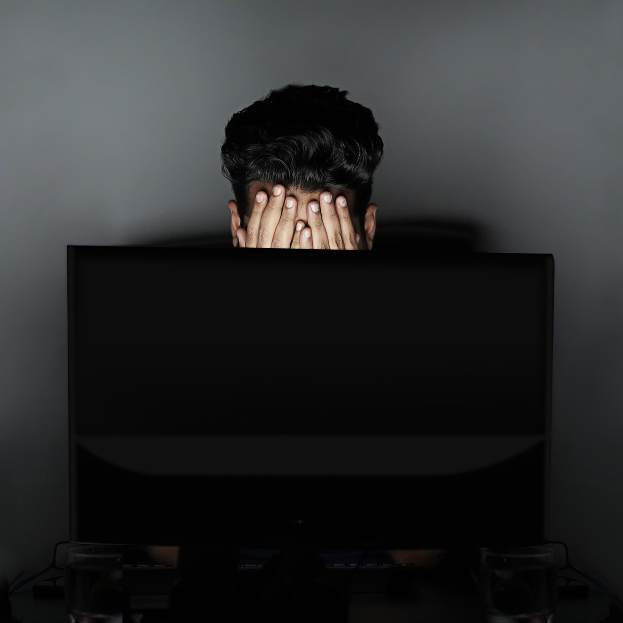 パソコンの前で仕事の負担を感じている人物